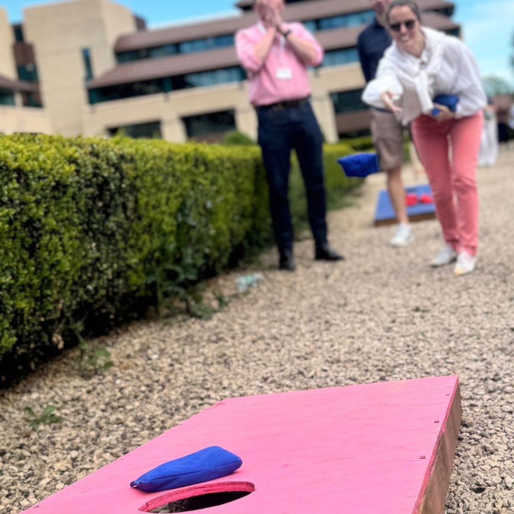 Women in sunglasses throwing a bean bag towards a cornhole board