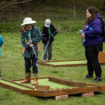 A scout playing mini golf