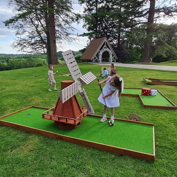 Children enjoying crazy golf at an outdoor wedding venue with handcrafted wooden mini golf course