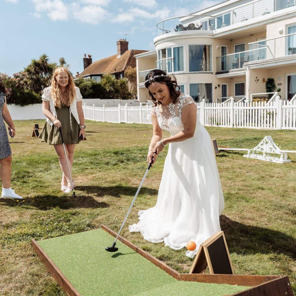 A woman on her wedding day playing crazy golf wearing a bridal dress