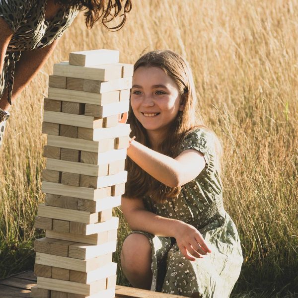Girl playing game of giant jenga with an adult